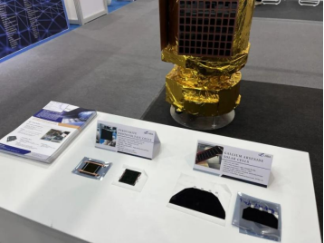 Solar-cell samples displayed beside a gold-covered satellite model.