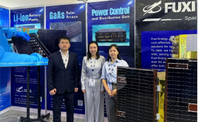 Three exhibitors posing beside solar-array and power-system displays.