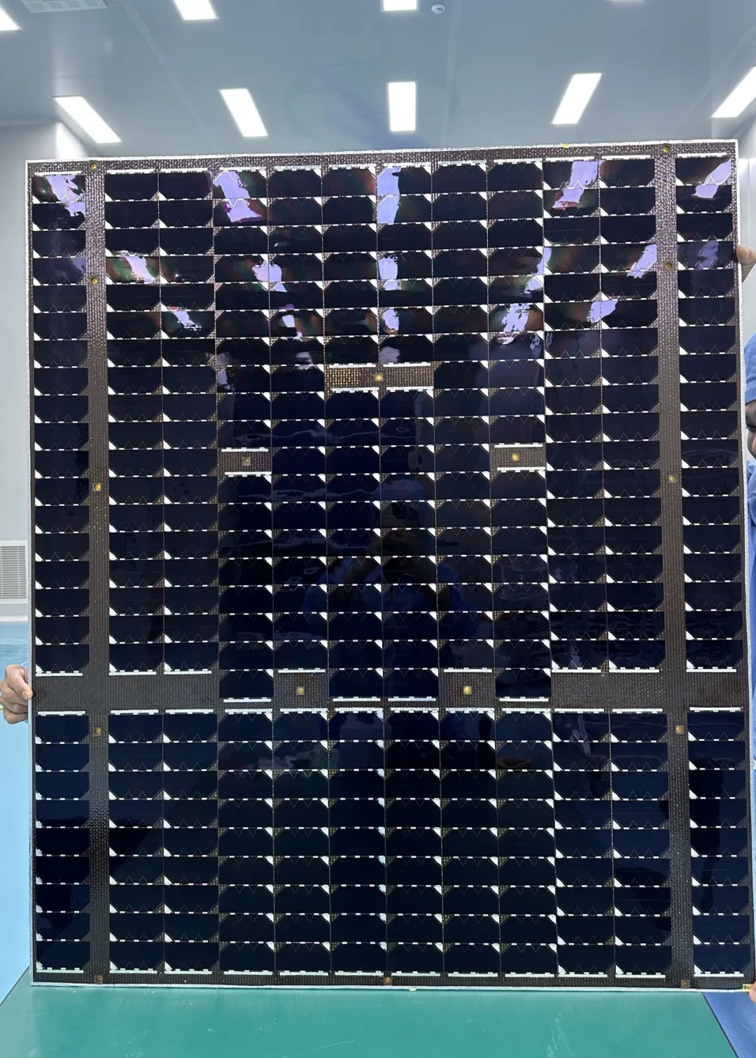 Rectangular solar array with rows of dark cells displayed upright indoors.