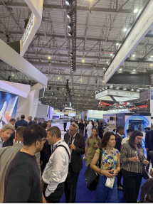 Busy exhibition aisle with visitors passing between aerospace displays.