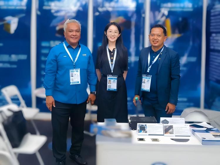 Three attendees posing behind a table of solar-cell samples at an exhibition.