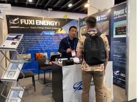 A visitor discussing a tabletop product display with a Fuxi exhibitor.
