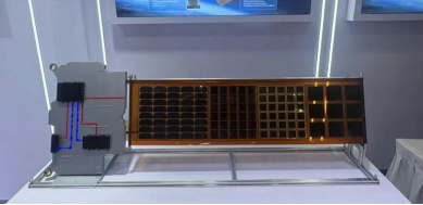 Solar-array and power-component demonstrator mounted horizontally in a display case.